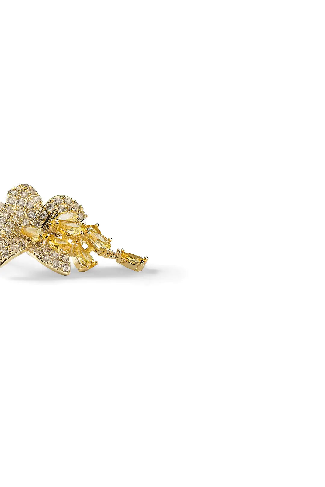 Side view of an Aiko Tanaka Yoka earring, a gold crystal blossom with a yellow drop, on a white background
