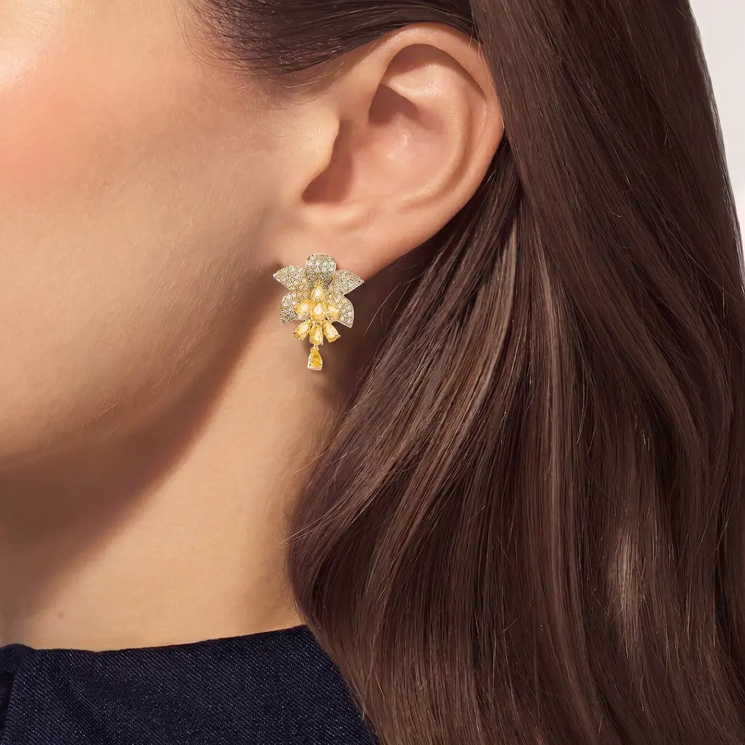 Close-up of a woman with long brown hair wearing the Aiko Tanaka Yoka gold crystal flower drop earring