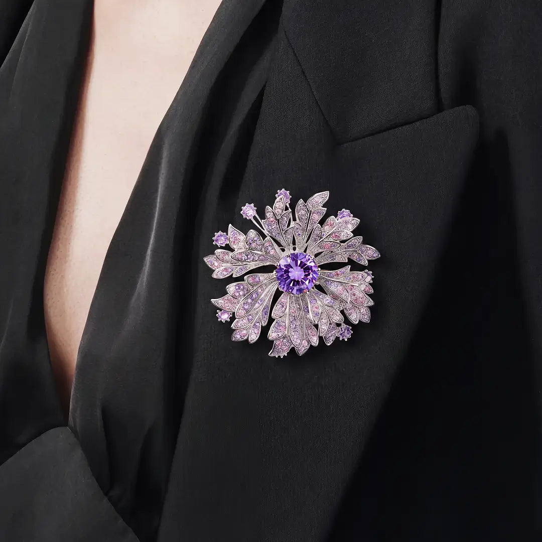 Aiko Tanaka Yozakura brooch, a lilac crystal flower with a purple center stone, worn on a black V-neck top