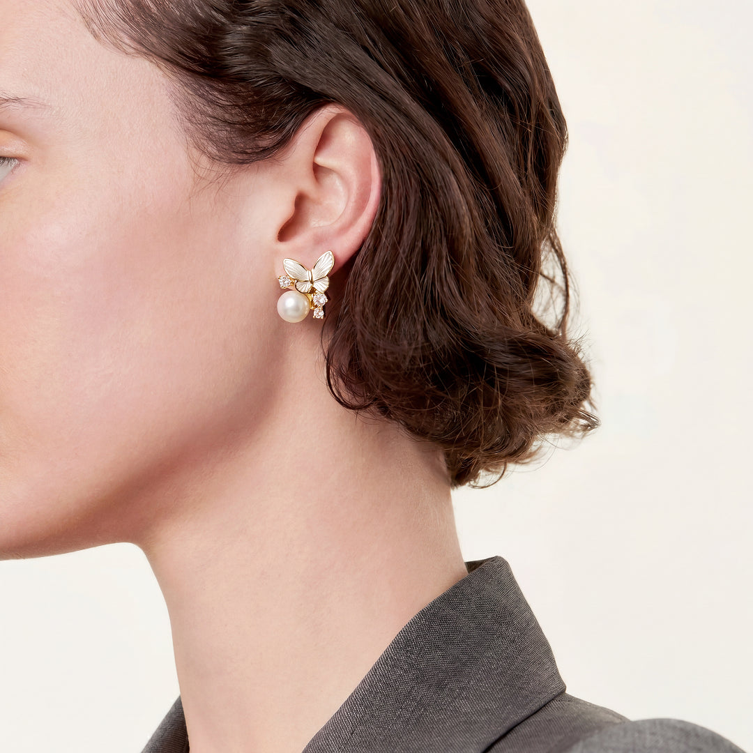 Woman in a grey blazer wearing the Aiko Tanaka Yuki Cho mother-of-pearl butterfly and pearl stud earring