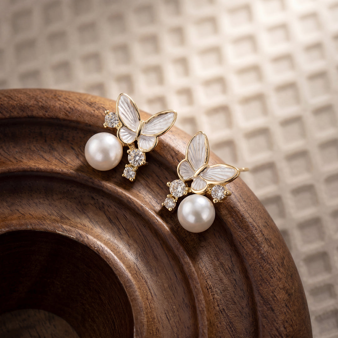 Aiko Tanaka Yuki Cho earrings with mother-of-pearl butterflies and white pearls on a carved wooden dish